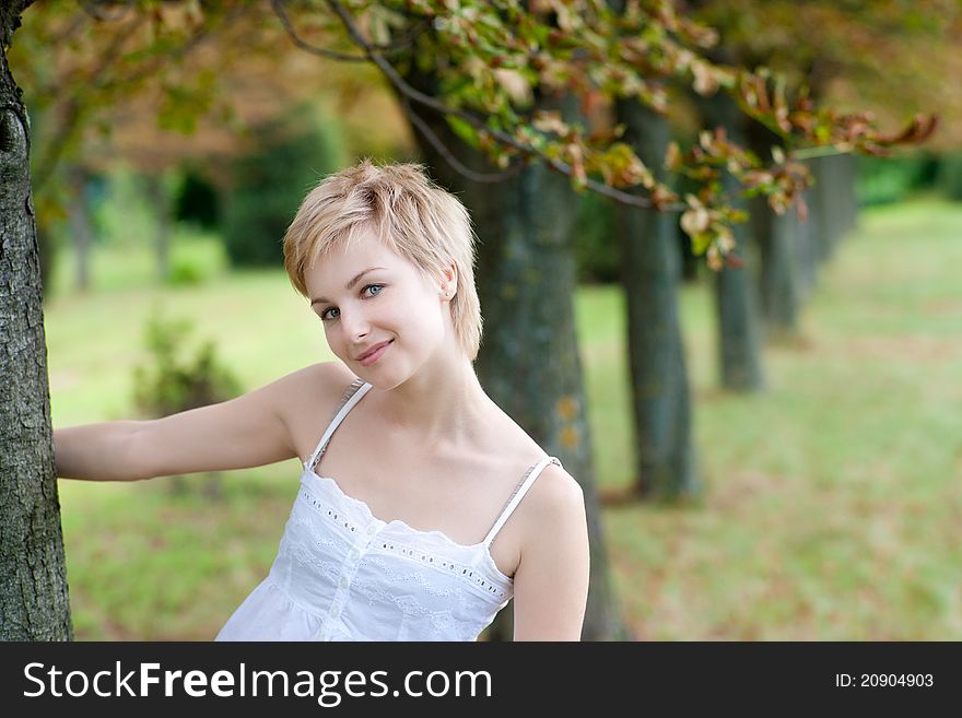 Portrait Of Young Smiling Woman Posing Near The Tr