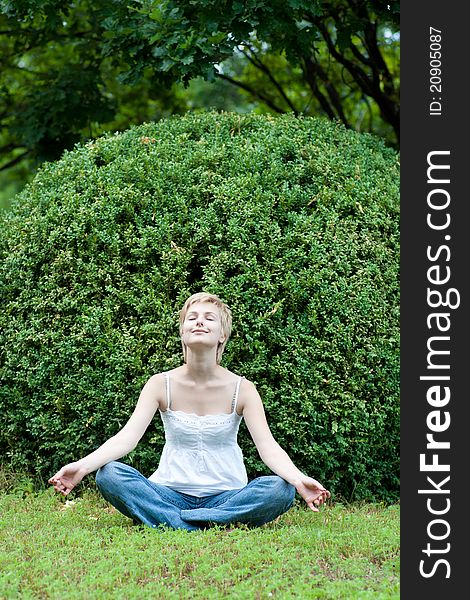Image of meditating girl seated in pose of lotus on green grass. Image of meditating girl seated in pose of lotus on green grass
