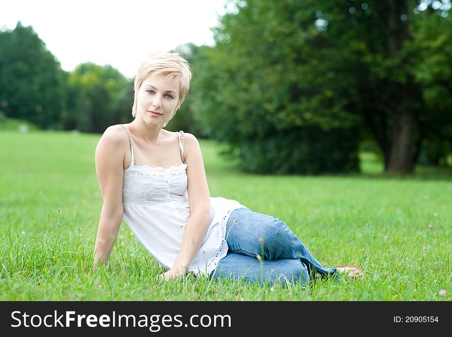 Beautiful Attractive Woman Sitting On A Green Gras