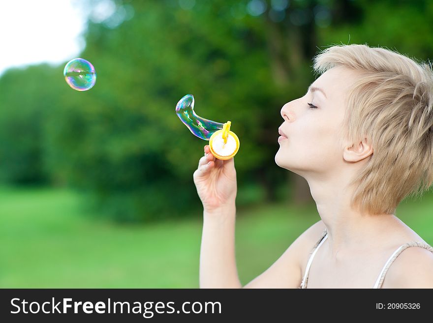Gorgeous young woman blowing soap bubbles in park. Gorgeous young woman blowing soap bubbles in park