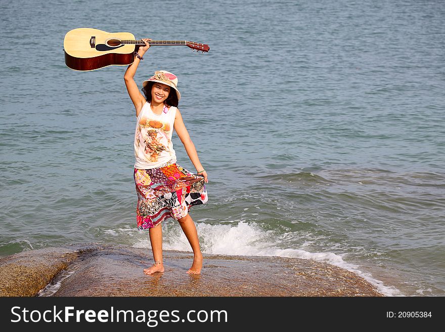 Pretty young woman with guitar on beach