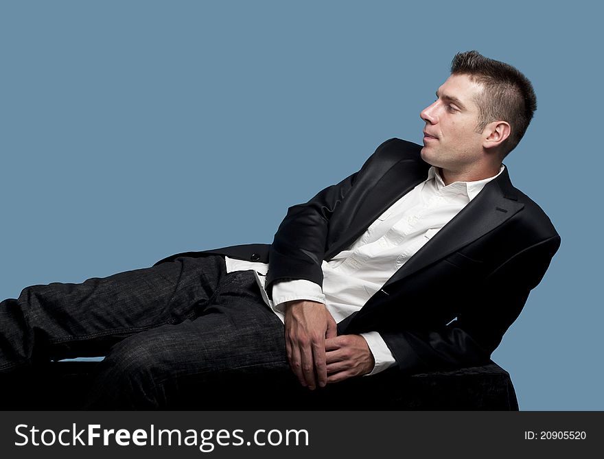 Young man  in suit relaxes on the bench at the studio. Young man  in suit relaxes on the bench at the studio