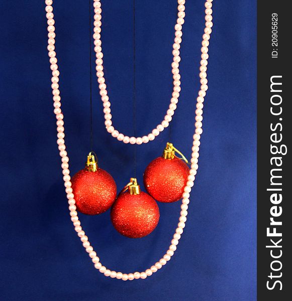 Beautiful two pearl chains with three red christmas balls on blue background