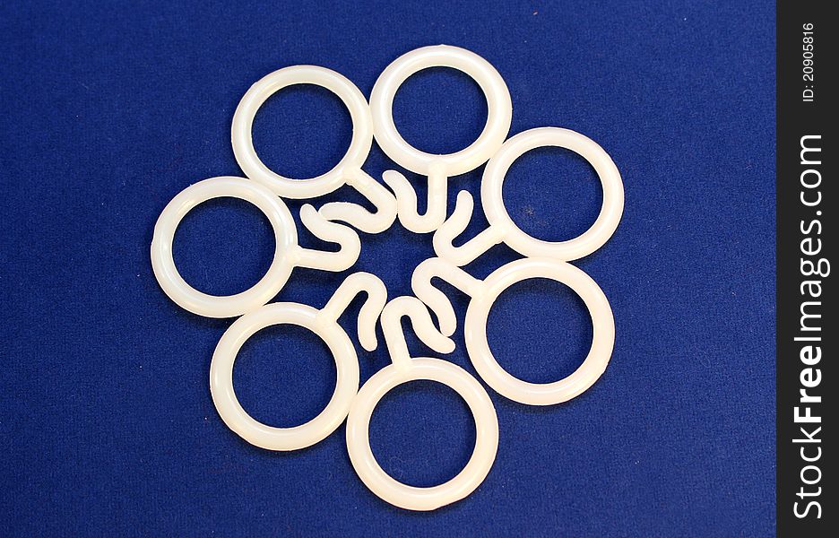Artistic display of white plastic curtain rings on blue background