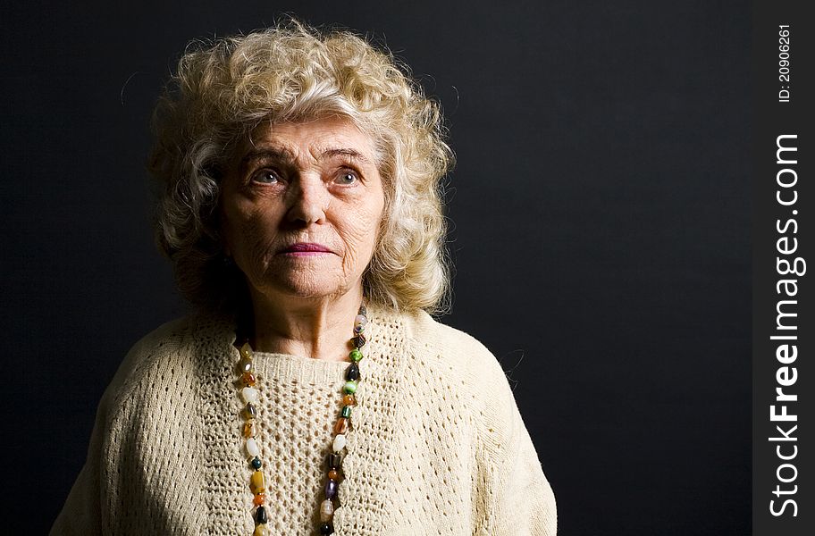 Portrait of woman in her eighties on black background. Portrait of woman in her eighties on black background