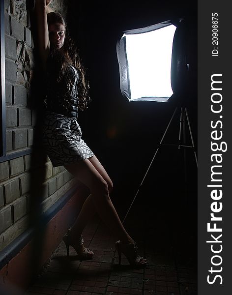 Girl leaning against a wall and a softbox