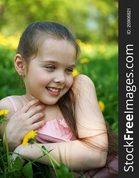 Little girl sits on a glade with dandelions