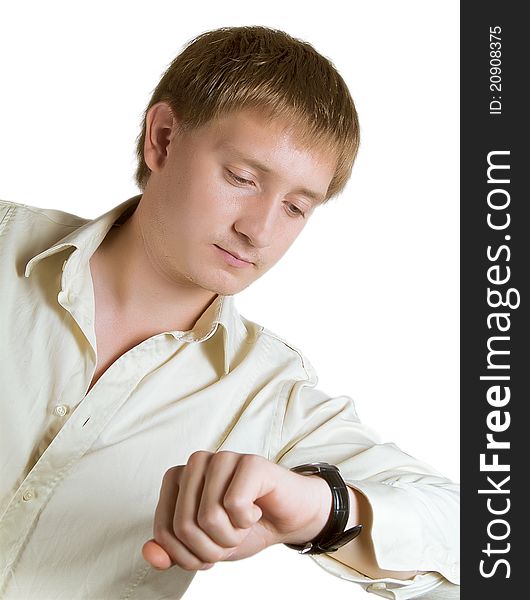 The young man in a light shirt looks at a watch. The young man in a light shirt looks at a watch