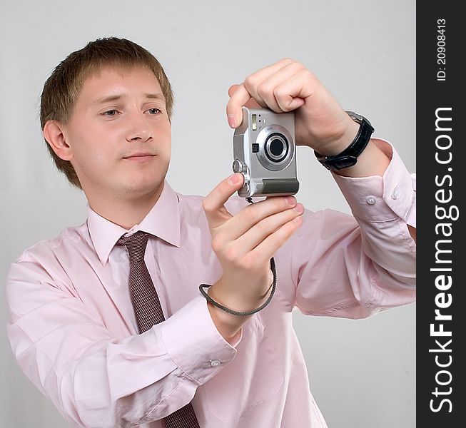 The young man photographed in studio, in a light shirt, with a tie, poses with the camera. The young man photographed in studio, in a light shirt, with a tie, poses with the camera