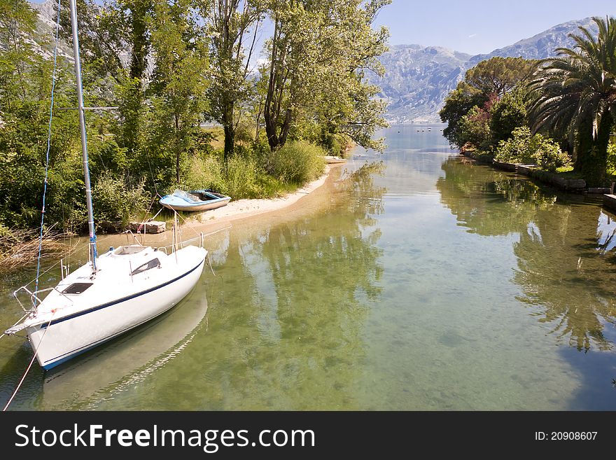 Small sailing boat on canal in Montenegro summer time. Small sailing boat on canal in Montenegro summer time.