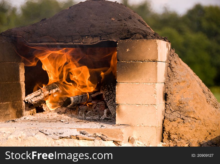 A hot fire burning in an earthen oven with a blackened top. The door is framed with bricks. A hot fire burning in an earthen oven with a blackened top. The door is framed with bricks.