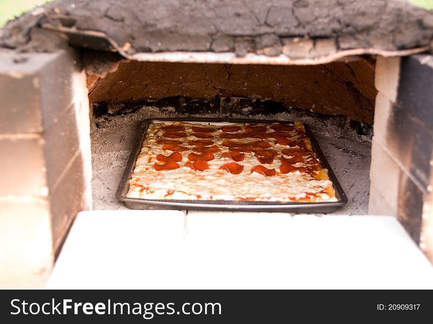 A pizza baking in an earthen oven. This is an old fashioned way of baking. A pizza baking in an earthen oven. This is an old fashioned way of baking.