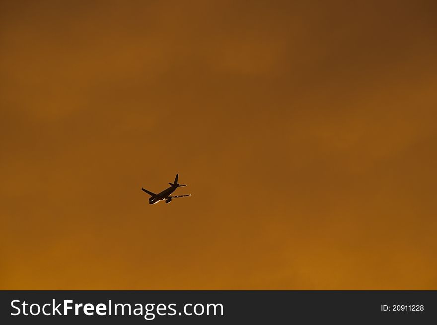 Airplane silhouette at sunset, cloudy sky