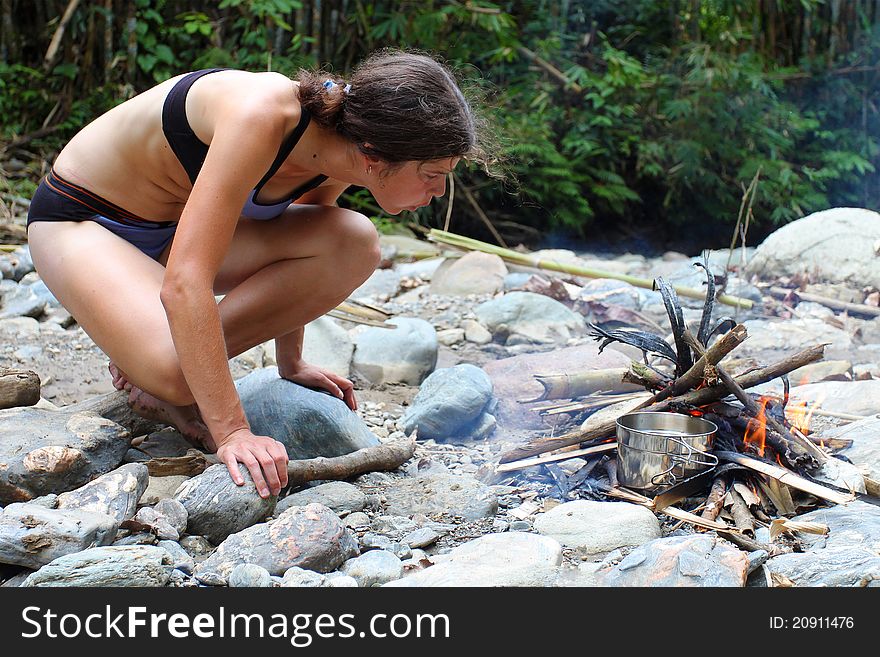 Young woman making a fire on pebble beach. Young woman making a fire on pebble beach