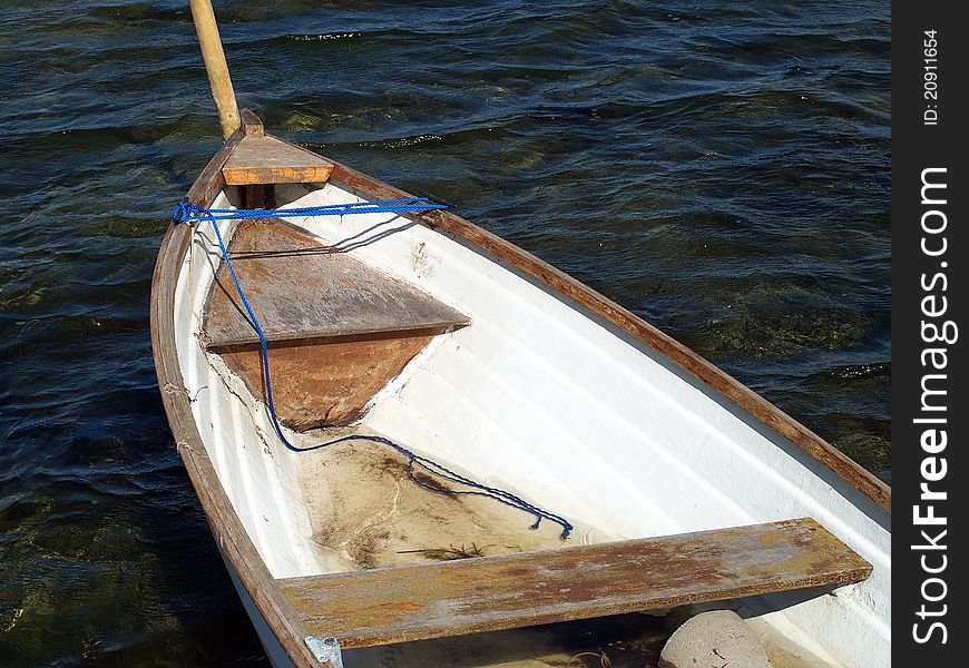 Small classical wooden fishing boat dory rowboat floating on sea water. Small classical wooden fishing boat dory rowboat floating on sea water