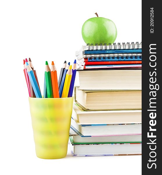 Textbooks and notebooks next to the pencils and green apple on top on white background. Textbooks and notebooks next to the pencils and green apple on top on white background