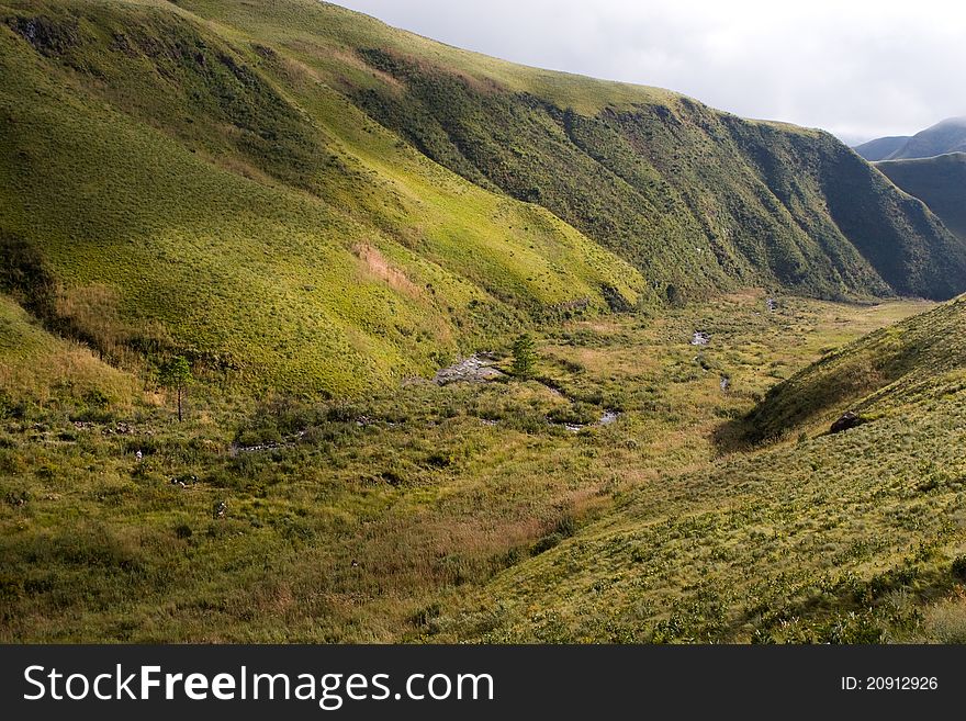 A group op people hiking next to a small stream in a large valley in south africa's drakensberg. A group op people hiking next to a small stream in a large valley in south africa's drakensberg