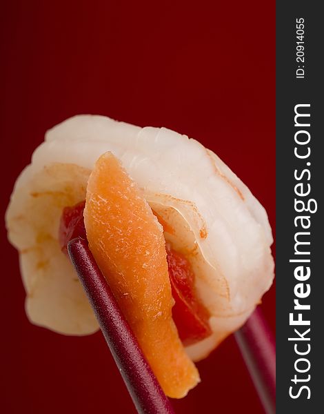 Shrimp from an appetizer in red chopsticks on a red background. Shrimp from an appetizer in red chopsticks on a red background.