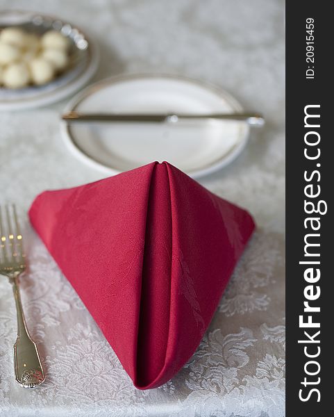 A folded red napkin and place setting are prepared for a diner.