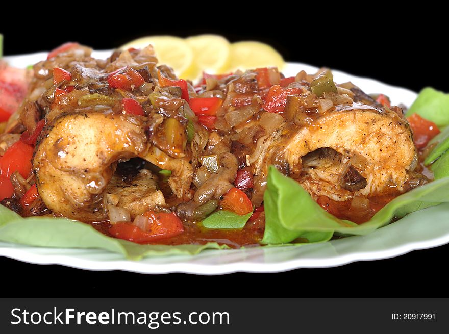 Baked fish on plate on black background