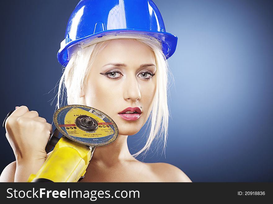 Beautiful topless model holds an angle grinder while wearing a blue construction helmet. Beautiful topless model holds an angle grinder while wearing a blue construction helmet.