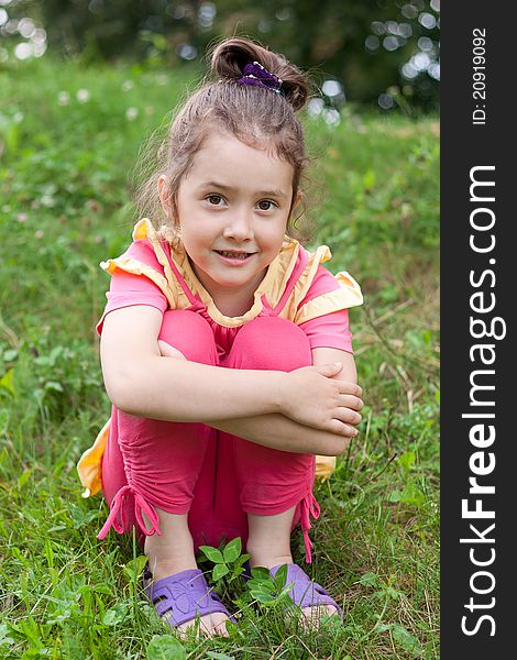 The little girl sits on a grass having drawn in knees. The little girl sits on a grass having drawn in knees