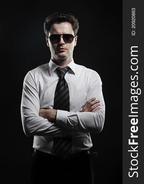 Portrait of a young businessman in sunglasses and white shirt.Isolated on a black background