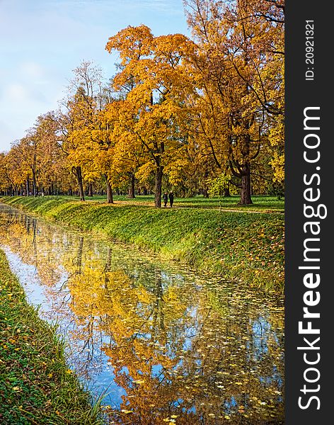 Golden autumn trees with reflection in water of canal