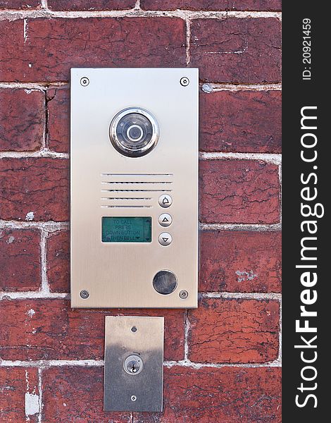 A metal security buzzer on a brick wall. A metal security buzzer on a brick wall