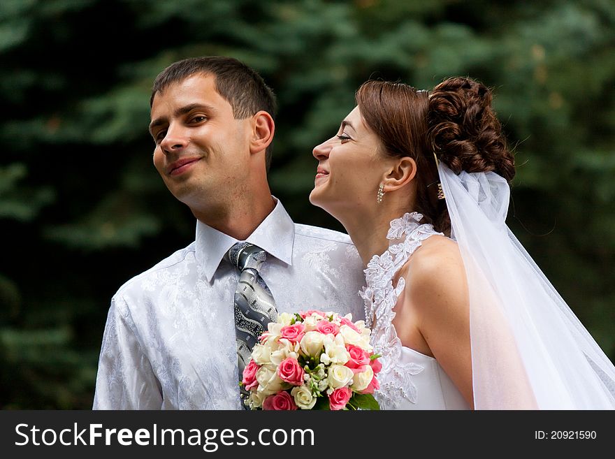 Happy bride trying to kiss the groom in the green alley