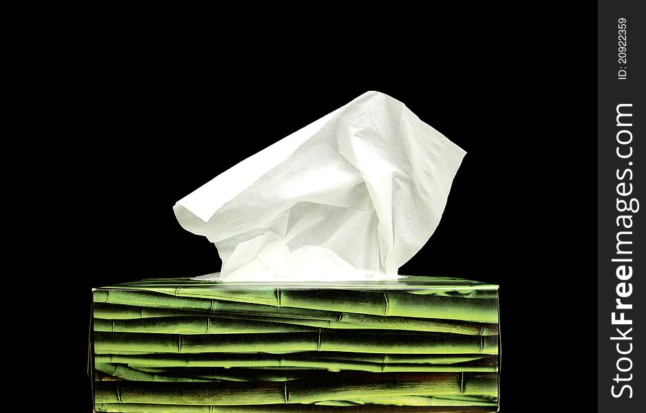 A green paper tissue box on a black background