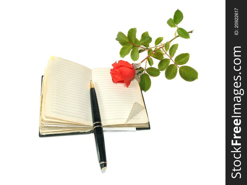 The notebook, the handle and red rose lie on a table. The notebook, the handle and red rose lie on a table
