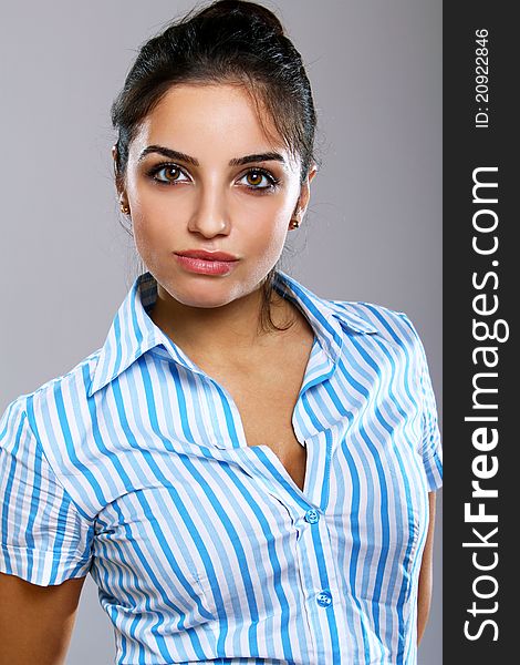 Young and beautiful woman in striped blouse over gray background
