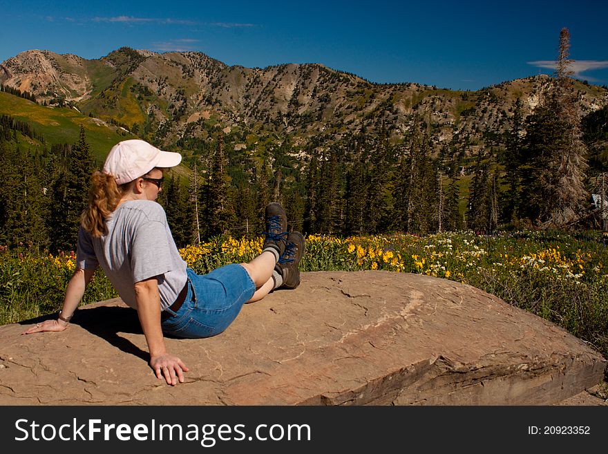 Image of a woman hiker resting on a rock in the mountains. Image of a woman hiker resting on a rock in the mountains