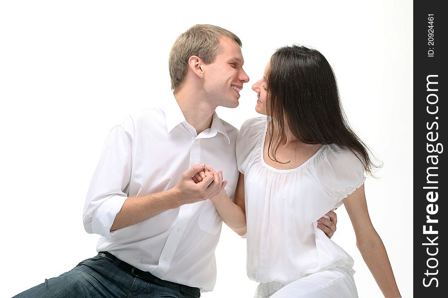 Couple in love: young man embracing young lady holding her hand; white background