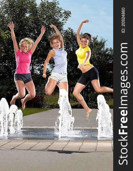 Three young women jumping in a fountain