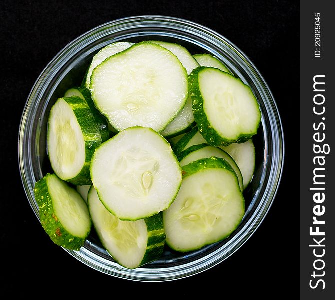 Cucumbers in a glass bowl on a black background