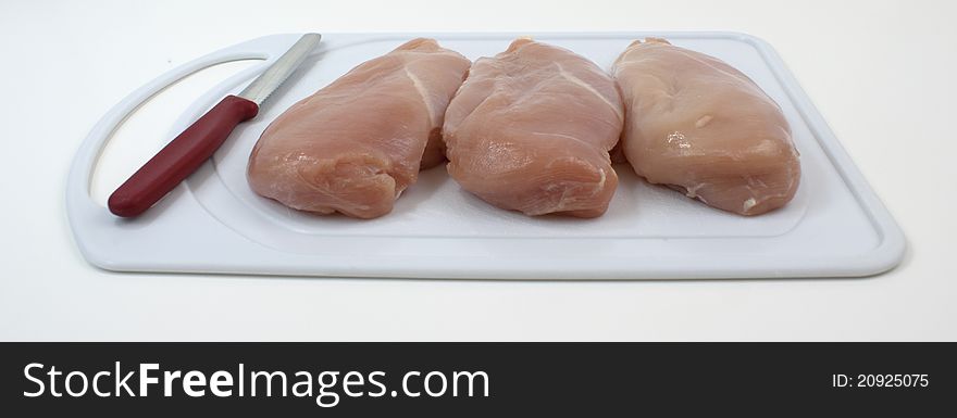 Chicken breasts on cutting board with knife