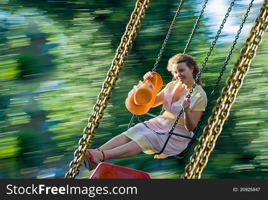 Beautiful young woman swinging and smiling. Image of swing blurred motion and happy girl at summer. Beautiful young woman swinging and smiling. Image of swing blurred motion and happy girl at summer.