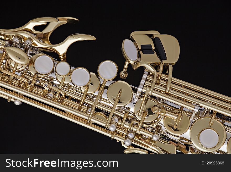 A gold and silver soprano saxophone isolated against a black background. A gold and silver soprano saxophone isolated against a black background.