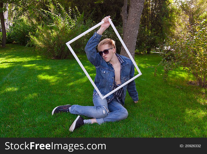 Young human on the green grass with white frame, he has blue goggles and jean jacket