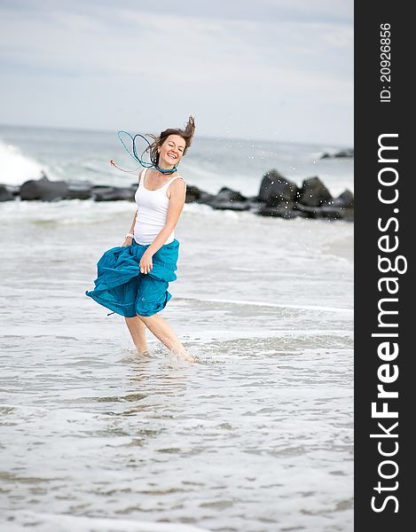 Beautiful woman in white cami and turquoise skirt has fun on the ocean shore. Beautiful woman in white cami and turquoise skirt has fun on the ocean shore