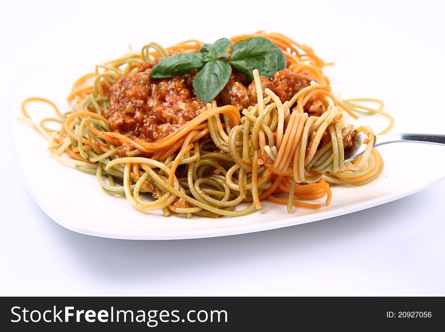 Spaghetti bolognese on a plate being eaten with a fork on white