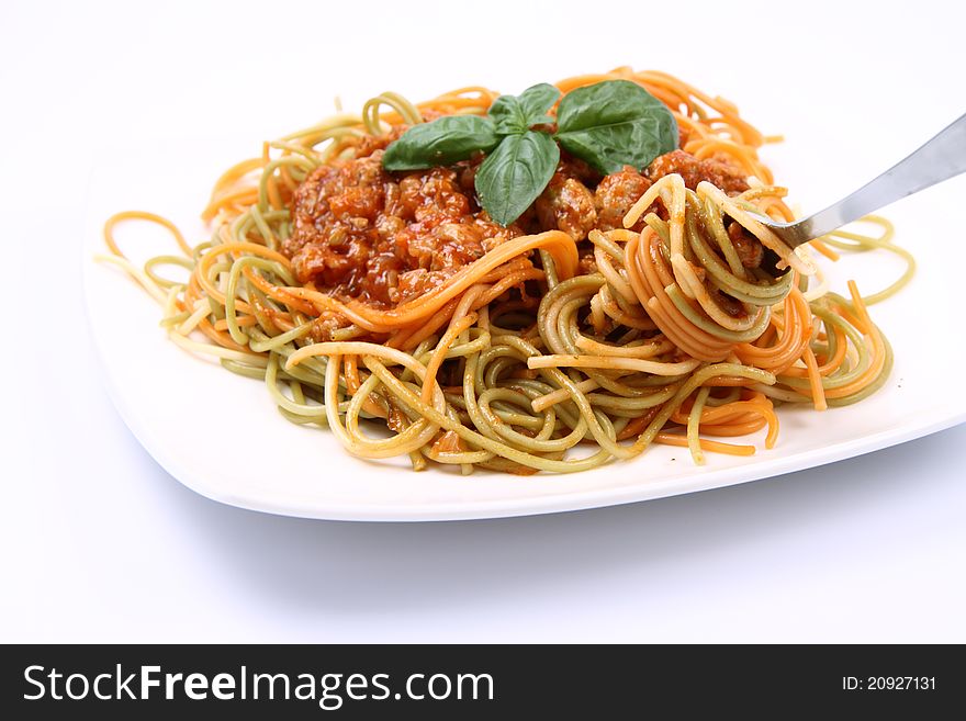 Spaghetti bolognese on a plate being eaten with a fork on white