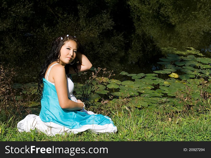 Beautiful pregnant girl walking in park near lake