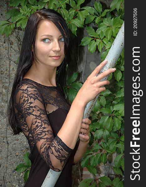 Female model holding handrail. Pretty Polish girl posing in front of green leaves. Female model holding handrail. Pretty Polish girl posing in front of green leaves.