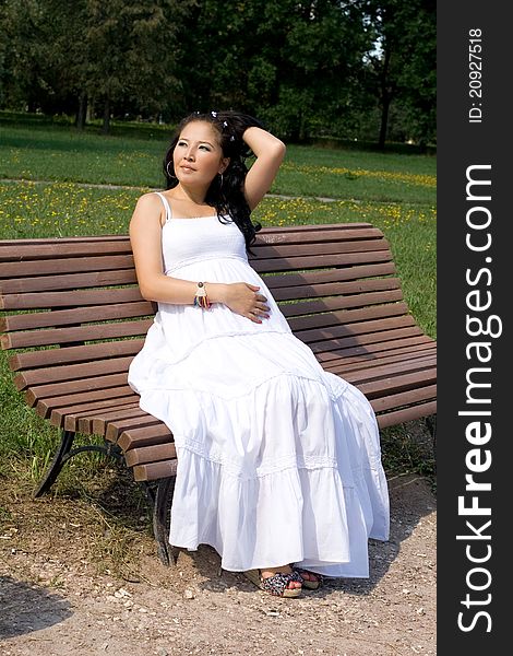 Beautiful pregnant girl resting on bench in park