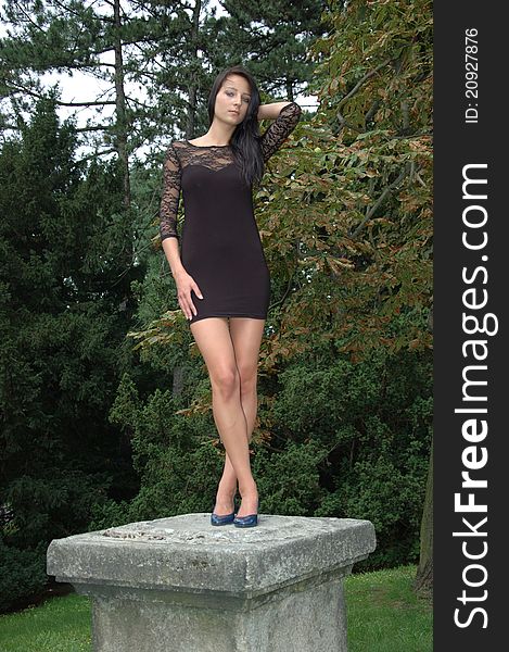 Female model posing as statue, standing on column. Polish girl wearing black dress. Female model posing as statue, standing on column. Polish girl wearing black dress.