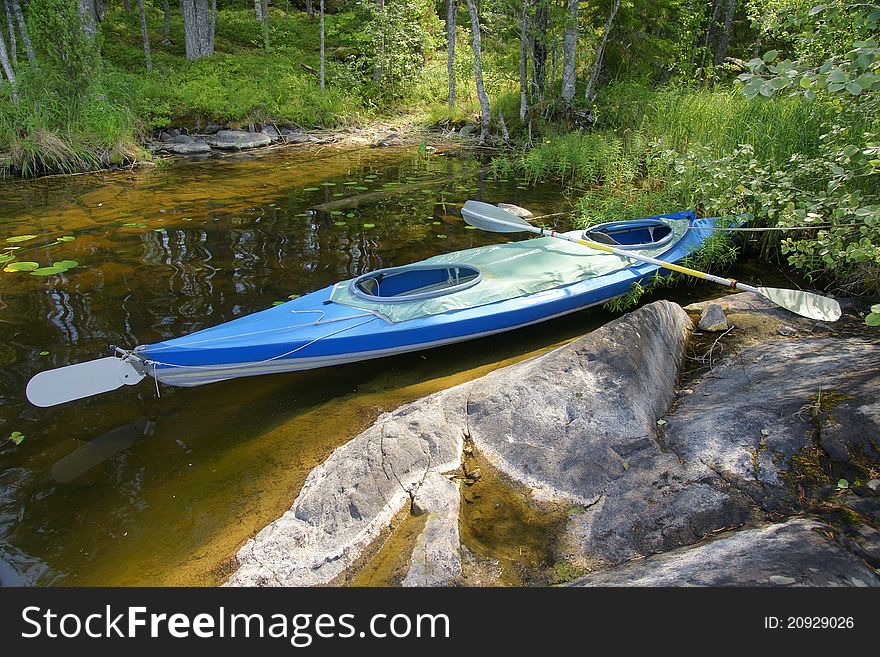 Blue canoe rests on shore of lake in summer (Onega Lake, Karelia, north-west European part of Russia). Blue canoe rests on shore of lake in summer (Onega Lake, Karelia, north-west European part of Russia)