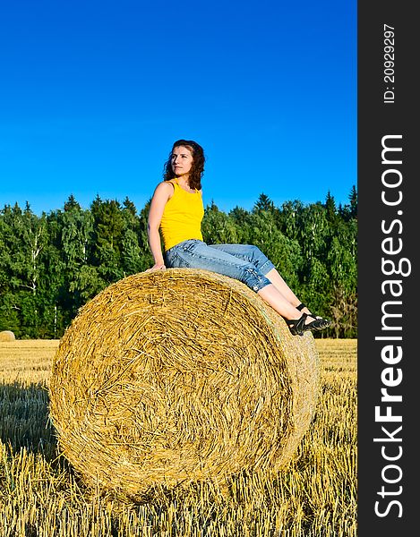 Young girl on a haystack in a field